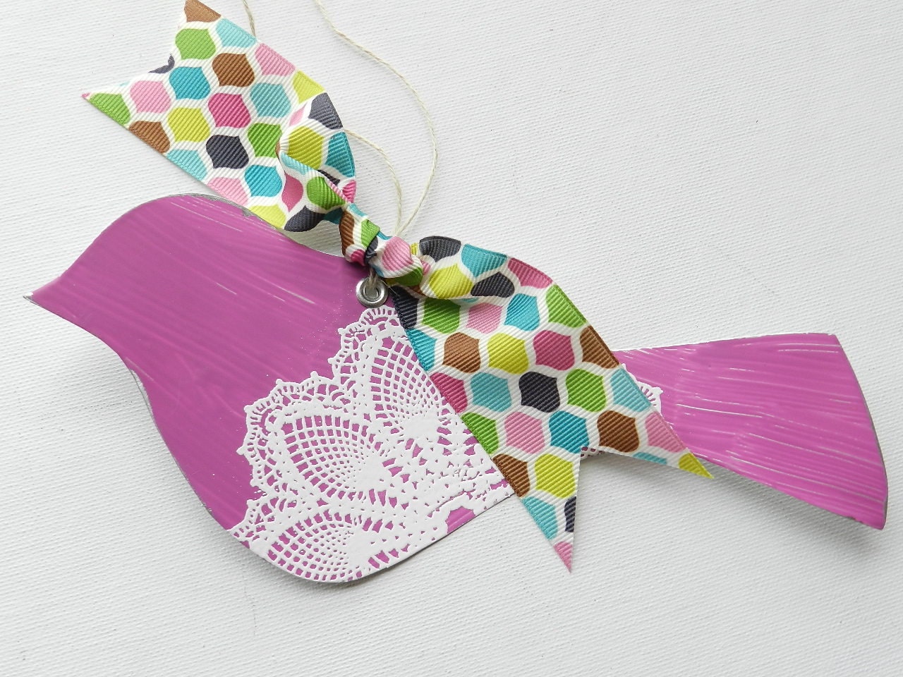 Magenta tin bird with white doily design and colorful ribbon to hang