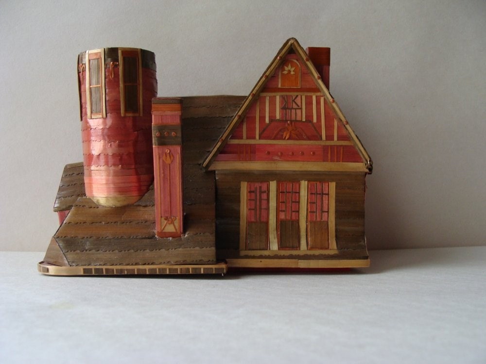 an intricate chalet made of grasses and paper probably made in germany and probably a candy box