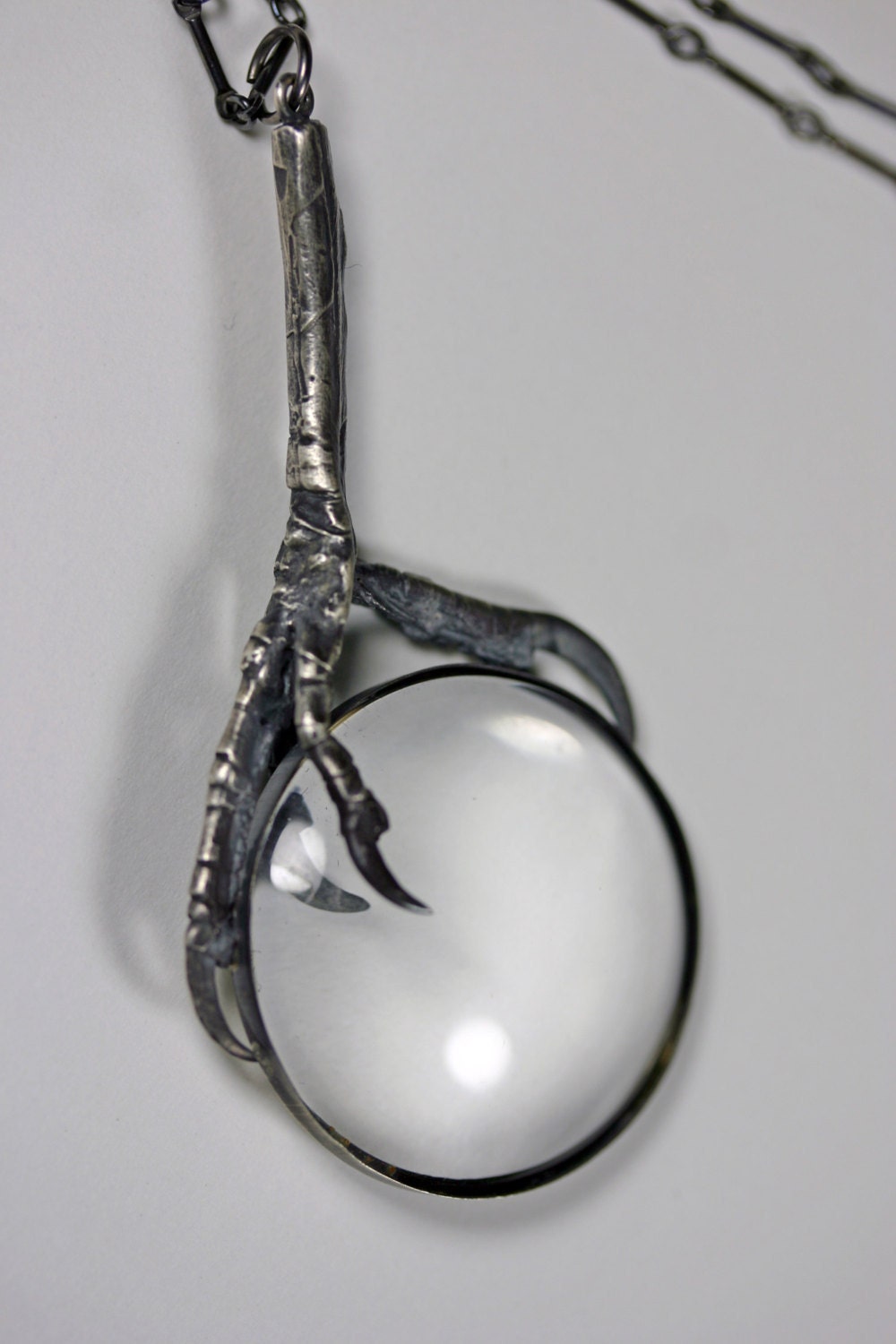 the oracle. magnifying glass and starling claw necklace.