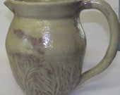Large carved pitcher with creamy white and red glaze