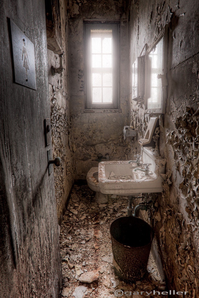 Ladies room - 8x12, 8x10 fine art photography print of a narrow crumbling lavoratory with an ethereal glowing light from the small window - garyhellerphotograph