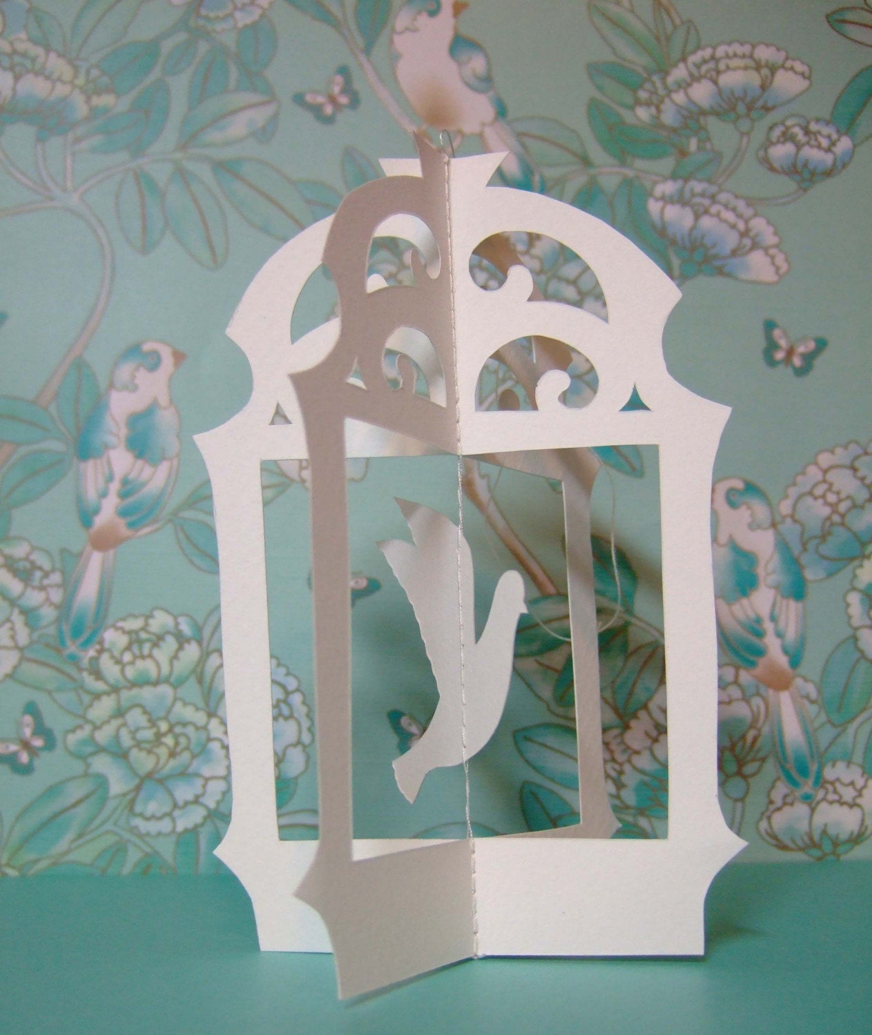 Original hand cut papercut of flying bird in cage - ivory