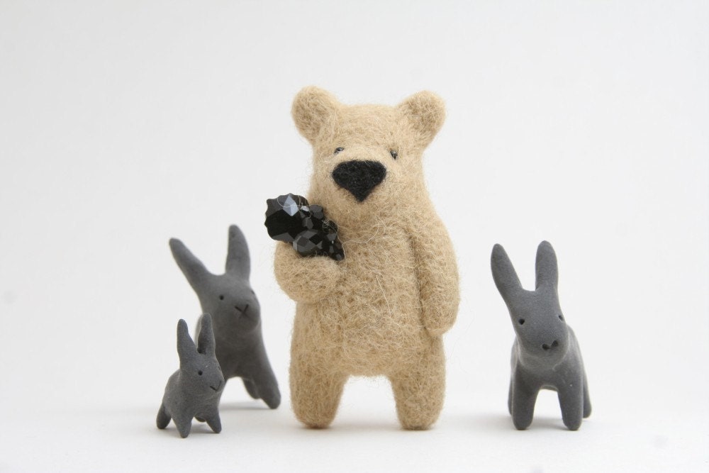 A beige bear with black crystals in paw, brooch