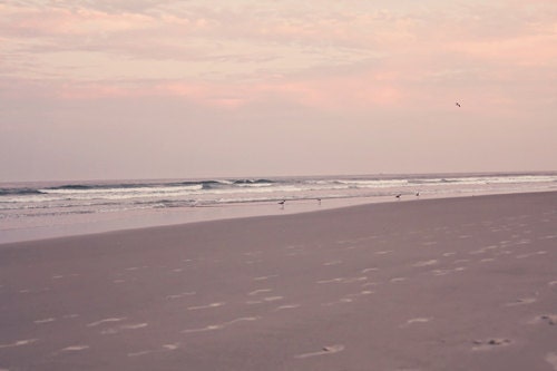 Summer ocean beach water sea nautical pale faded women sand tan brown under 50 light pink sky clouds beige waves - Fine Art Photography