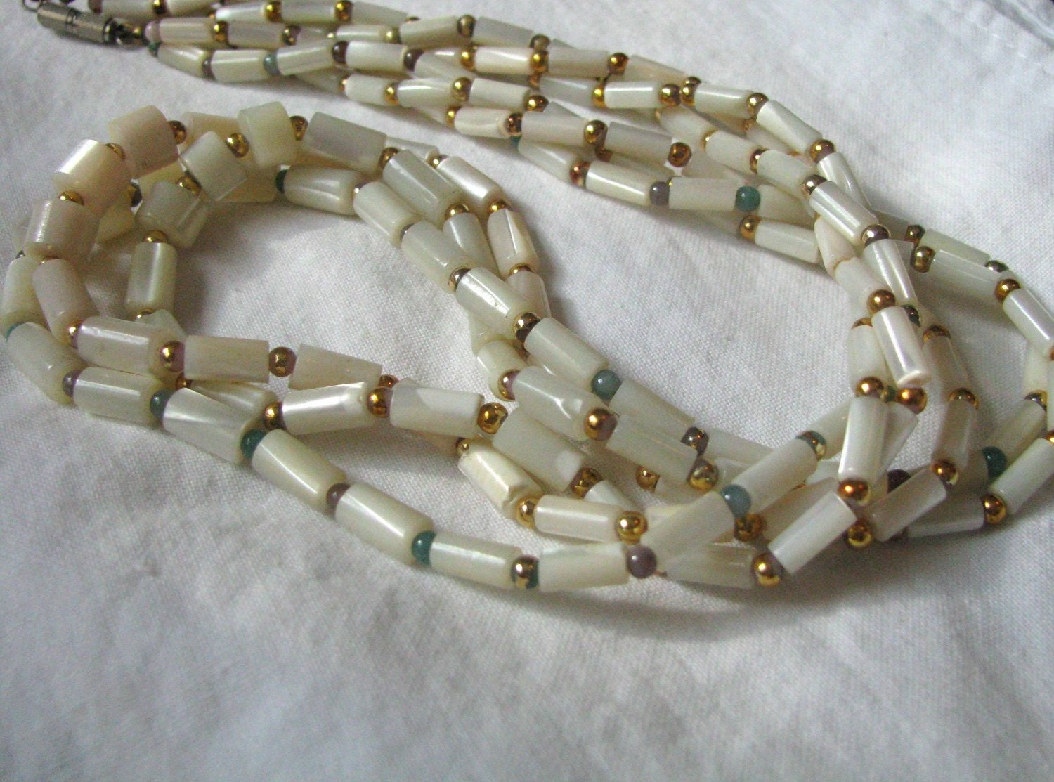 Triple strand necklace mother of pearl look oval & long beads.