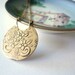 Gold necklace flower pendant. Detailed brass disk suspended from a delicate 14K gold fill chain.