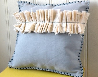 Small gray decorative pillow with cream muslin ruffle