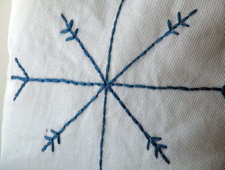 Small white cotton decorative pillow with blue embroidered snowflake