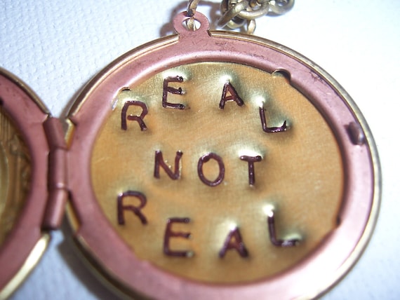 The  Hunger Games real not real hand stamped Peeta's  locket with mockingjay