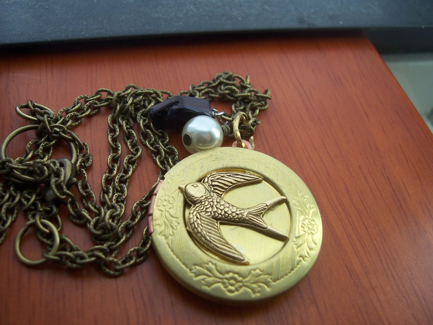 The  Hunger Games real not real hand stamped Peeta's  locket with mockingjay