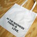 in the madness, there is love tote bag - black text