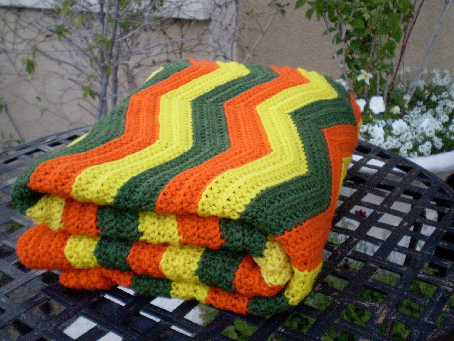 A vintage 1960s 1970s orange yellow and green chevron pattern knit crochet afghan granny blanket