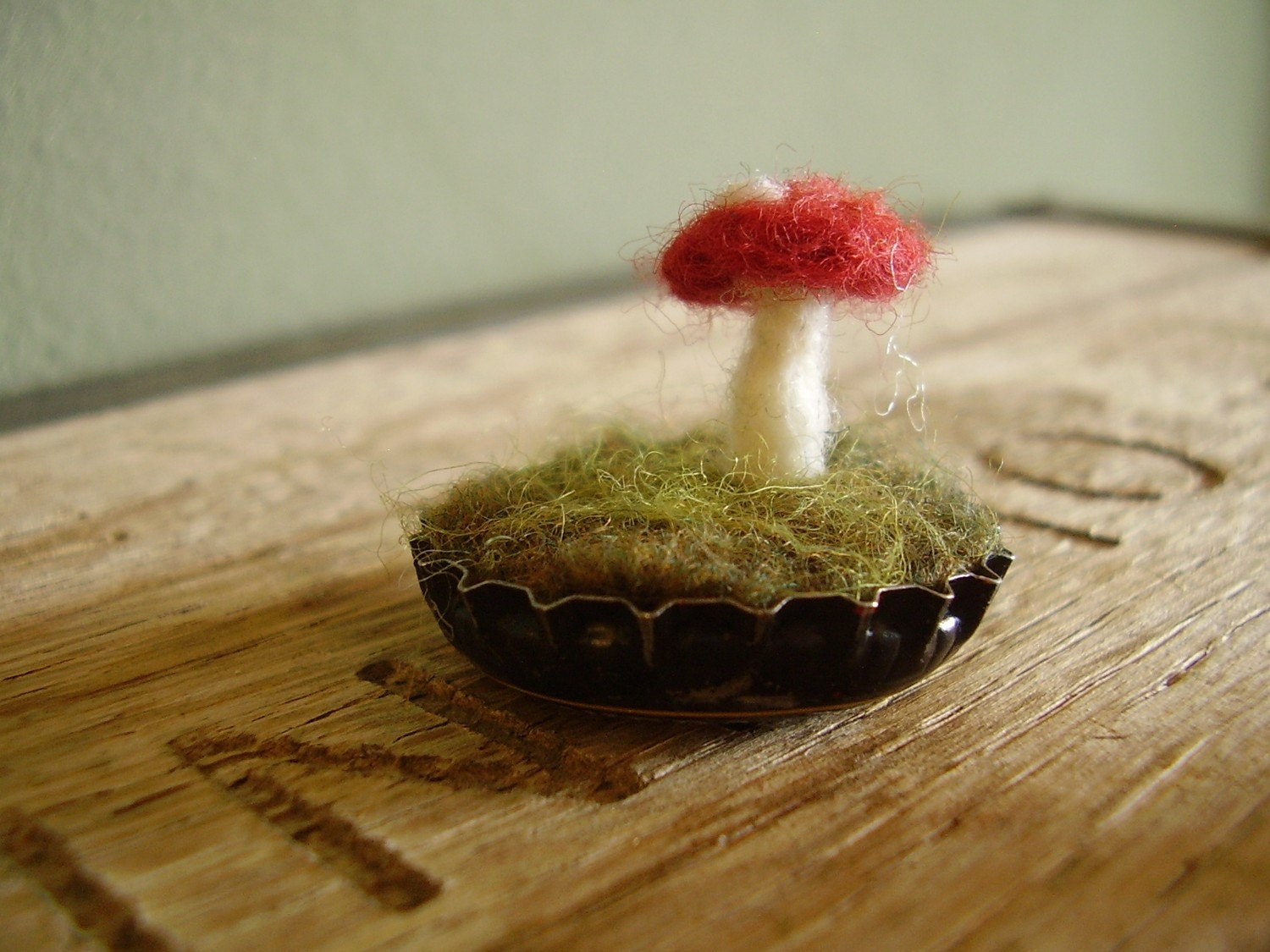Felted red amanita mushroom in an upcycled black bottlecap