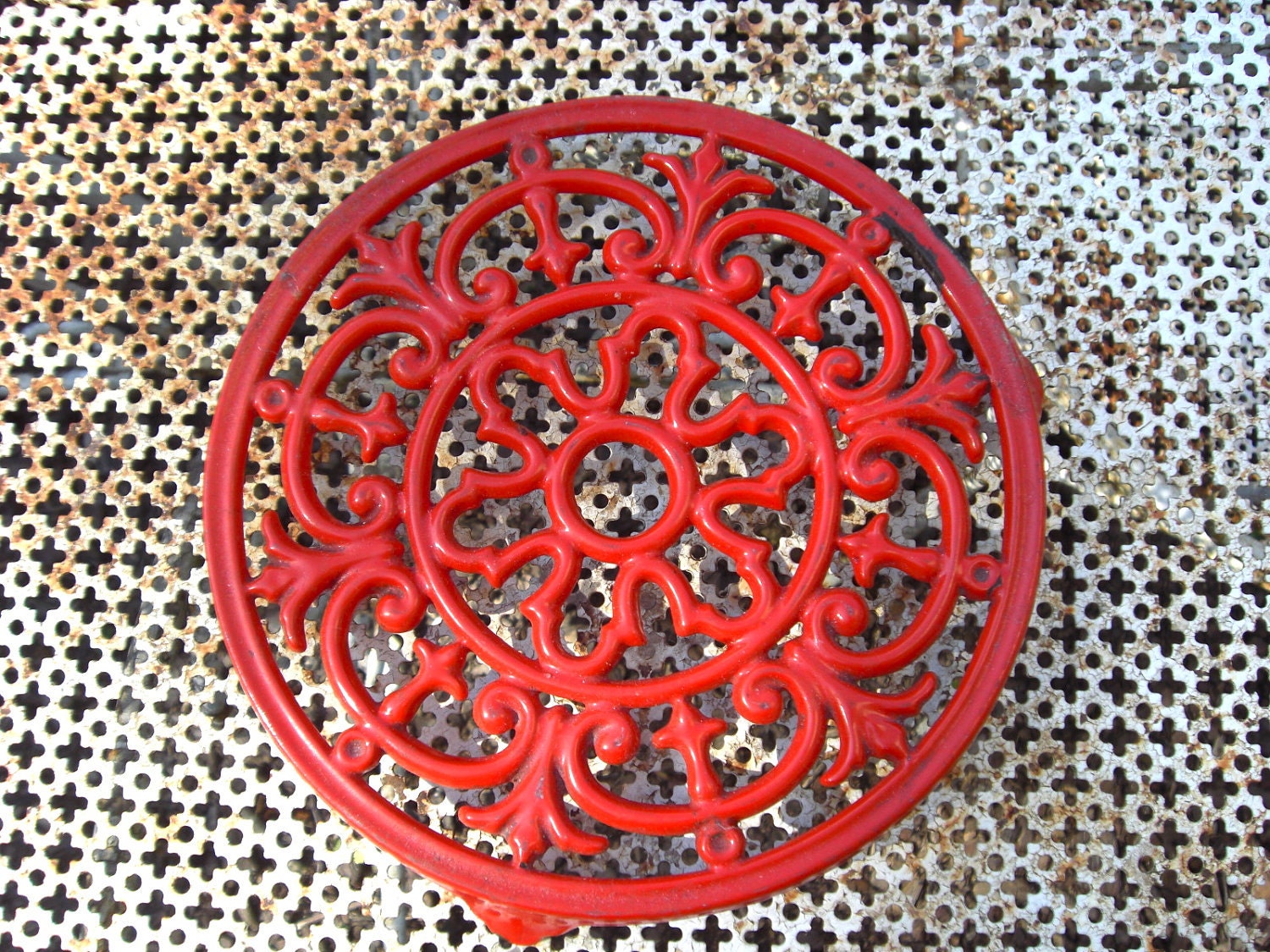 Antique art nouveau red cast iron trivet.