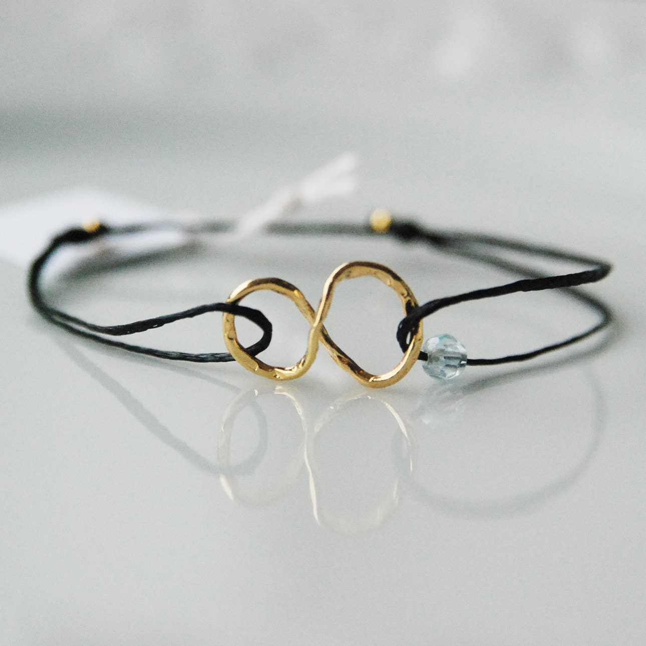 Gold infinity bracelet on black cord