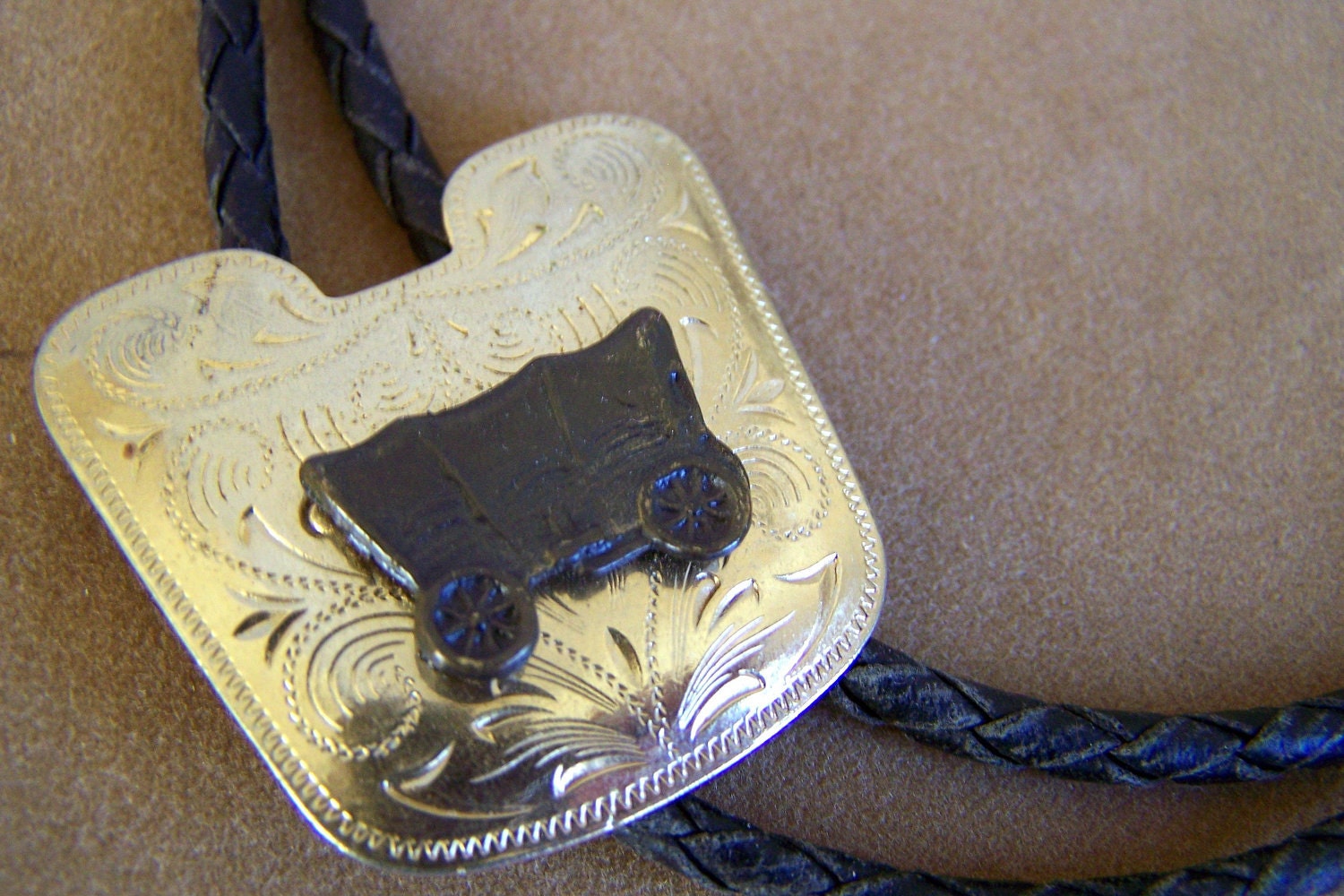 Vintage 60's Bolo Tie Gold Toned Engraved Shield Covered Wagon Design  Leatherette Braided Cord