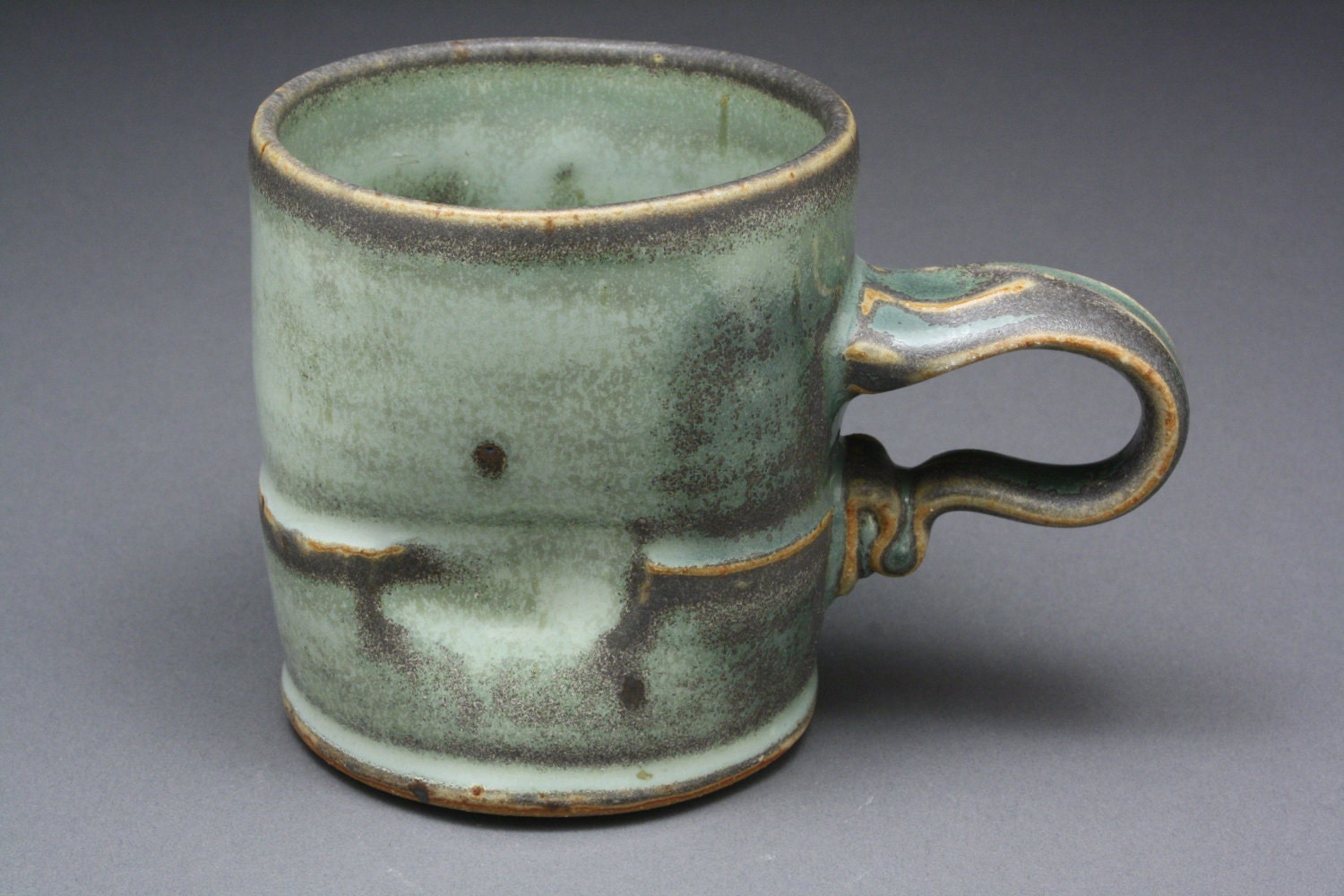 Coffee mug with splotchy dark green glaze