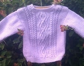 Child's handknit mauve aran sweater with shoulder openings.