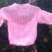 Girl's handknit pink aran sweater with back opening.