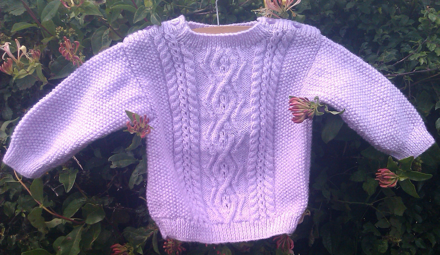 Child's handknit mauve aran sweater with shoulder openings.