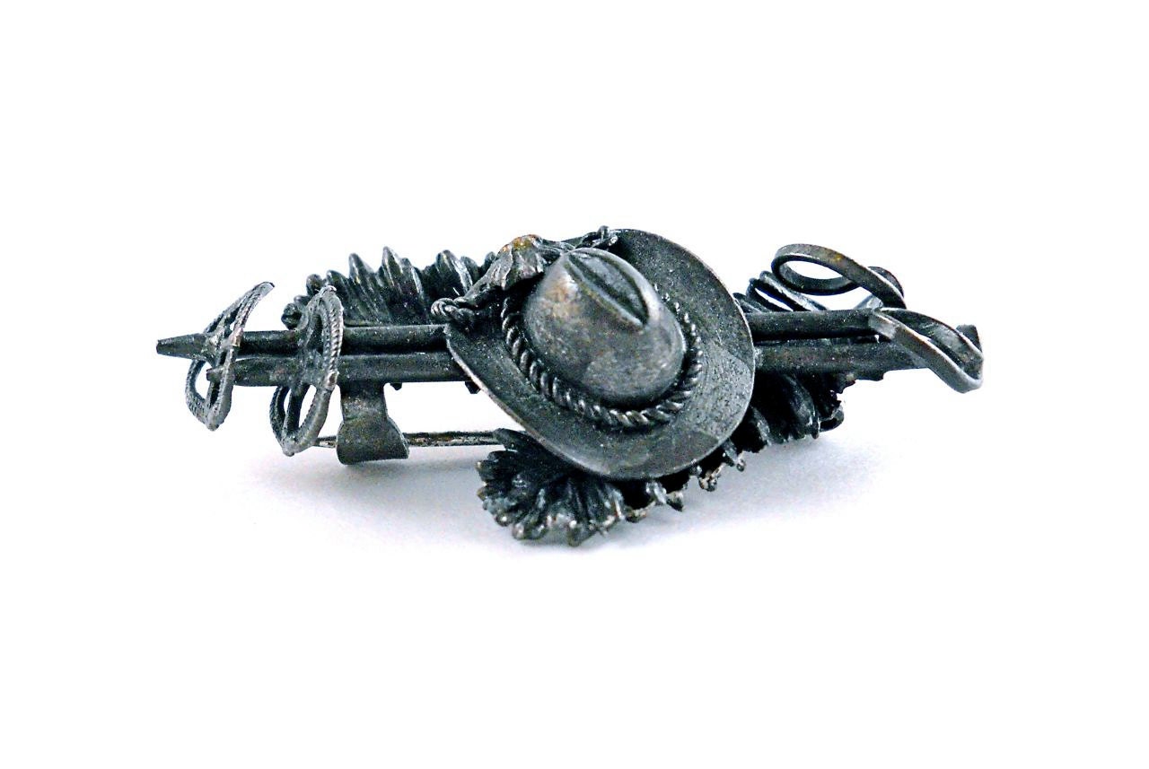 Unique Vintage Brooch with a cowboy hat and related items on it.