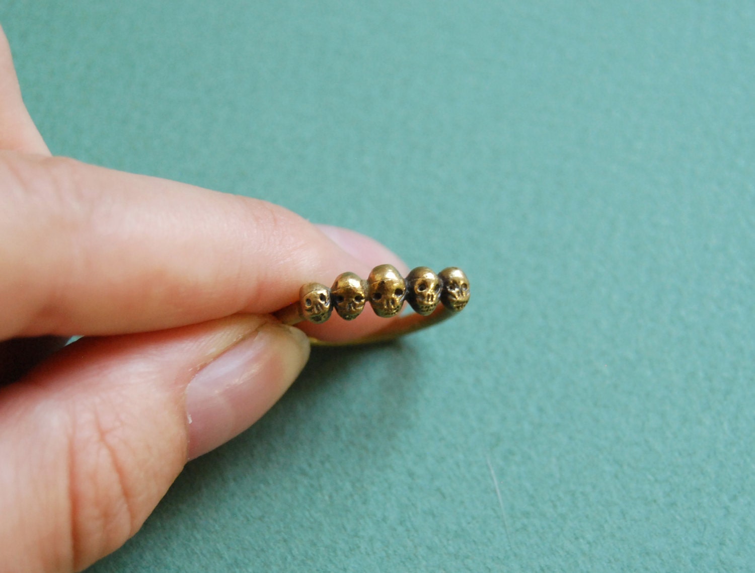 Golden row of tiny skulls ring