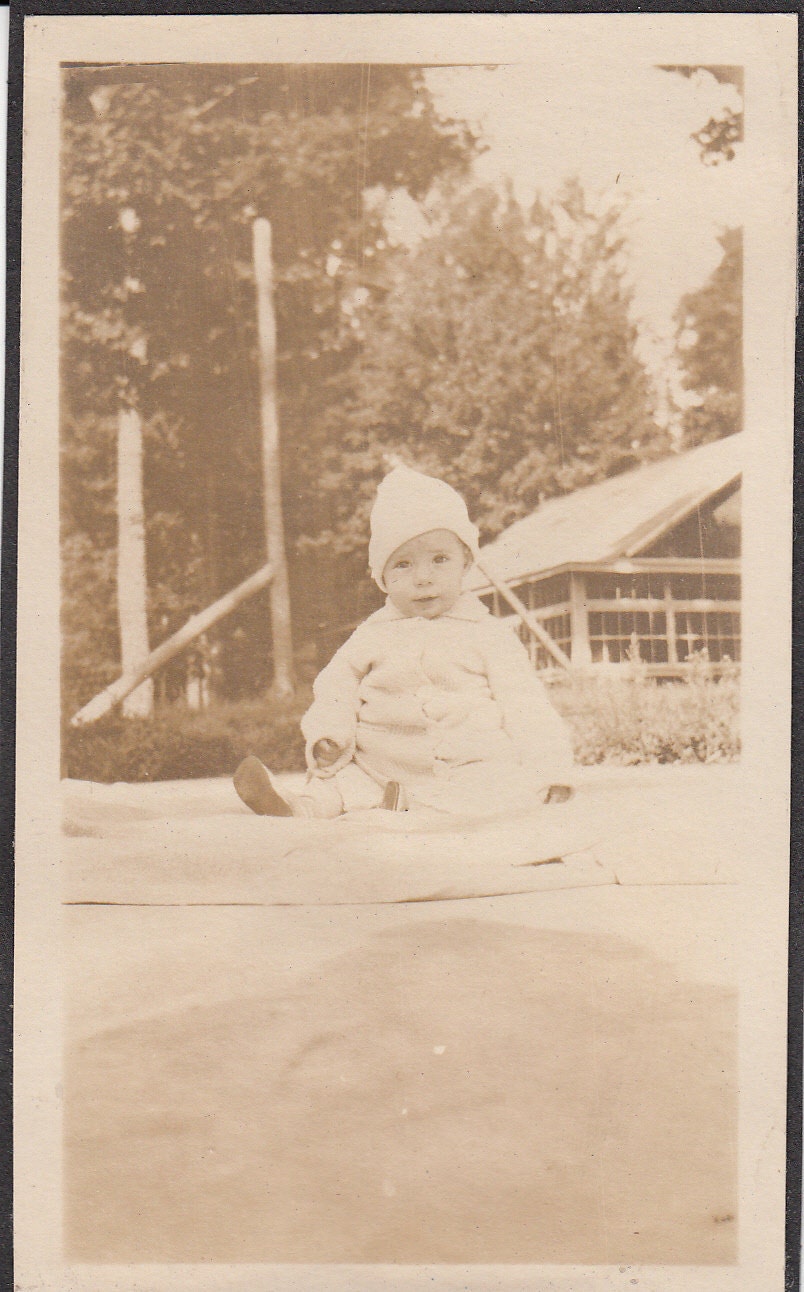 Vintage/ Antique photo of a cute baby sitting on a blanket outside