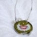 Green embroidered necklace of a mightily winged smile wrapped in typewriter keys "Pneumothorax"