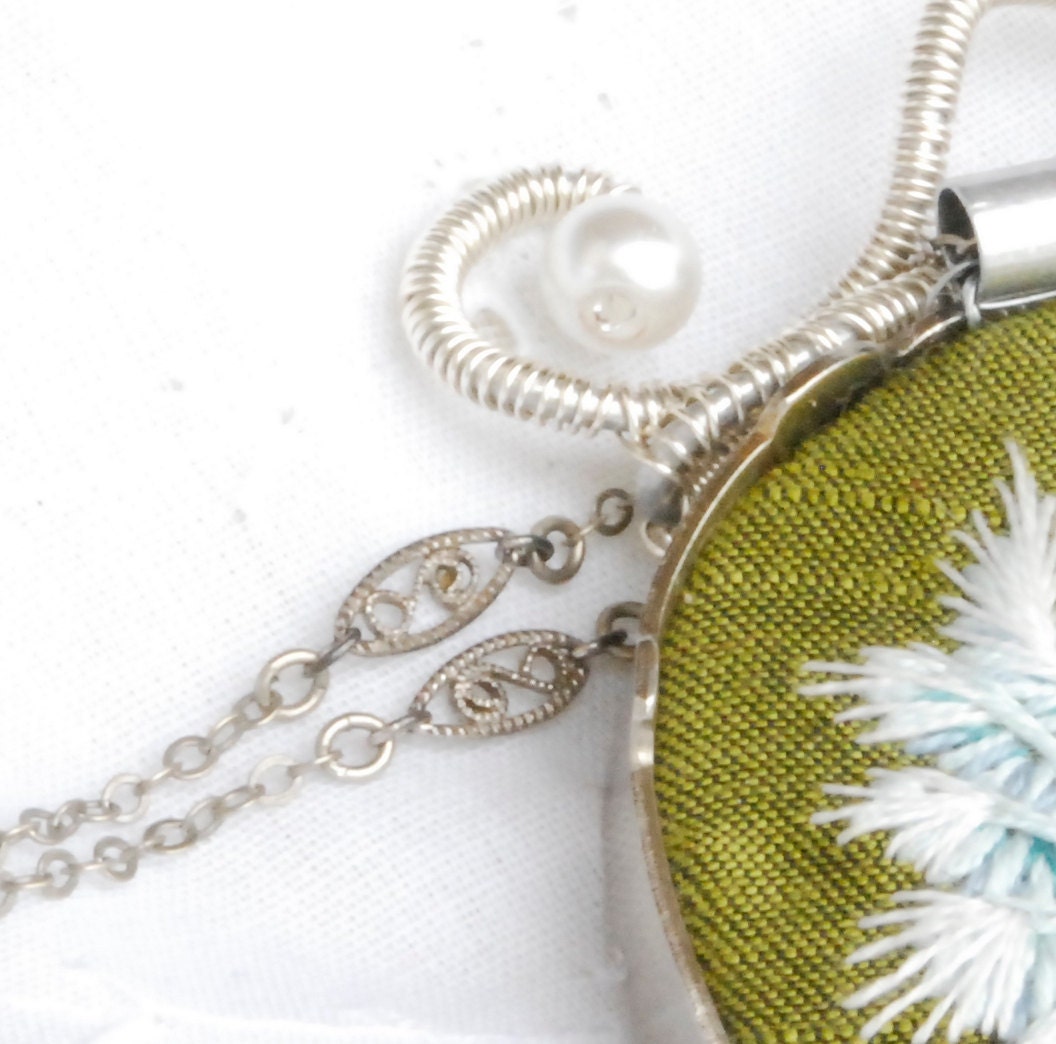 Green embroidered necklace of a mightily winged smile wrapped in typewriter keys "Pneumothorax"