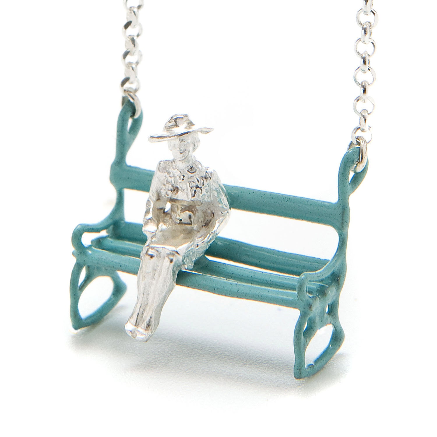 Silver necklace with a lady  who is sitting on a pale blue bench