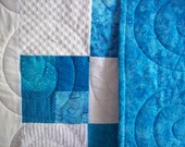 Aqua baby quilt / childs blanket with white textured fabrics and quilted all over with swirl pattern