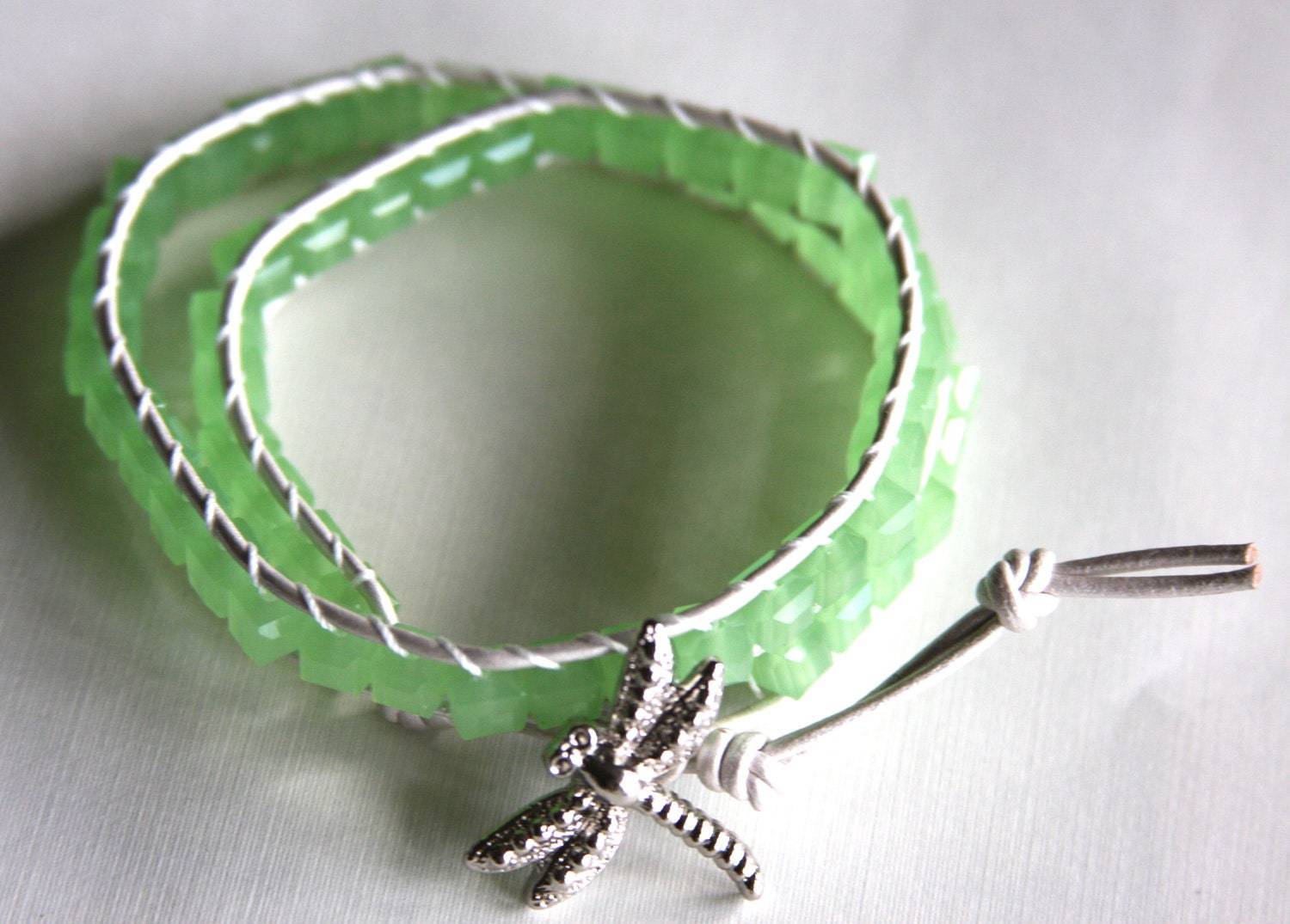 Leather wrap bracelet made with pearl colored leather, lime green cube crystals and silver dragonfly button clasp