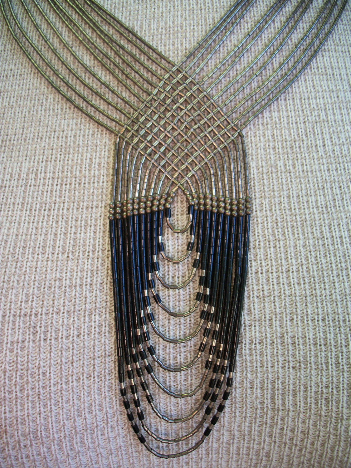 Tribal necklace, metallic and black beaded strands woven together in unique pattern.