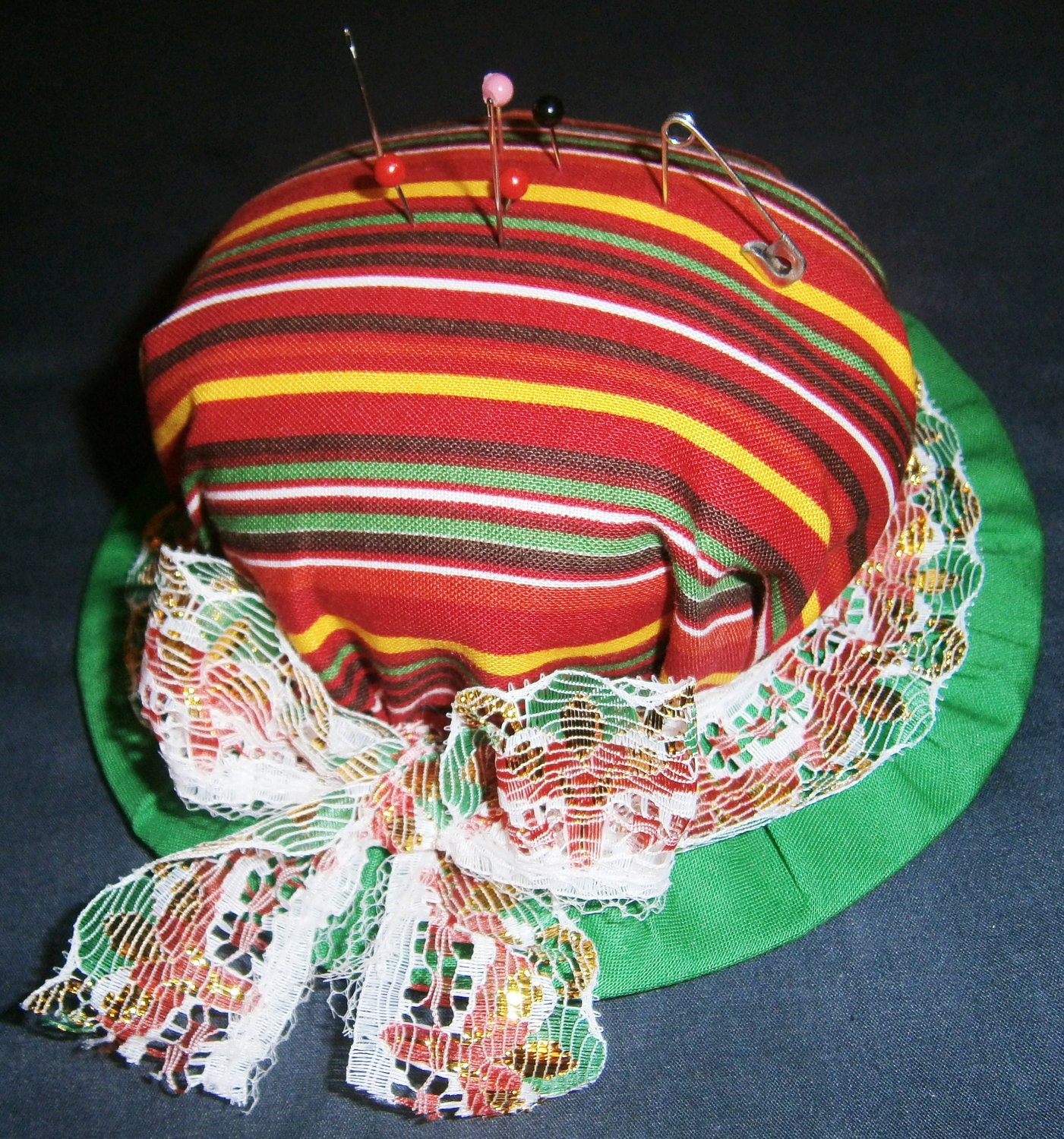 Striped top with a green base hat shaped pin cushion with multicolor lace ribbon