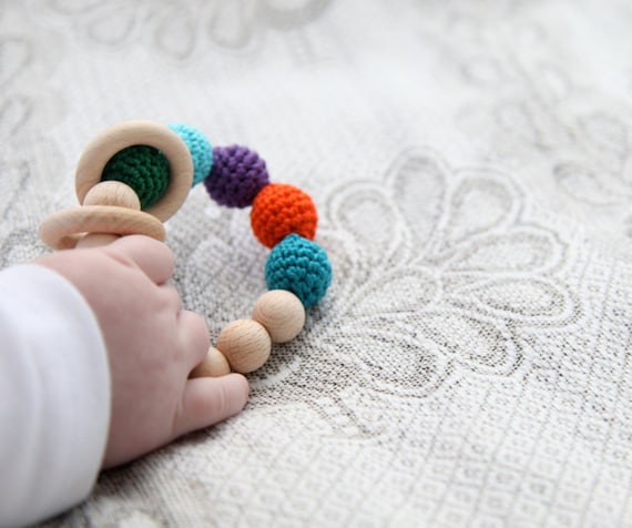 Peacock rattle. Teething ring toy with crochet wooden beads. Bright orange, blue, smaragd  green, violet, teal, cyan..