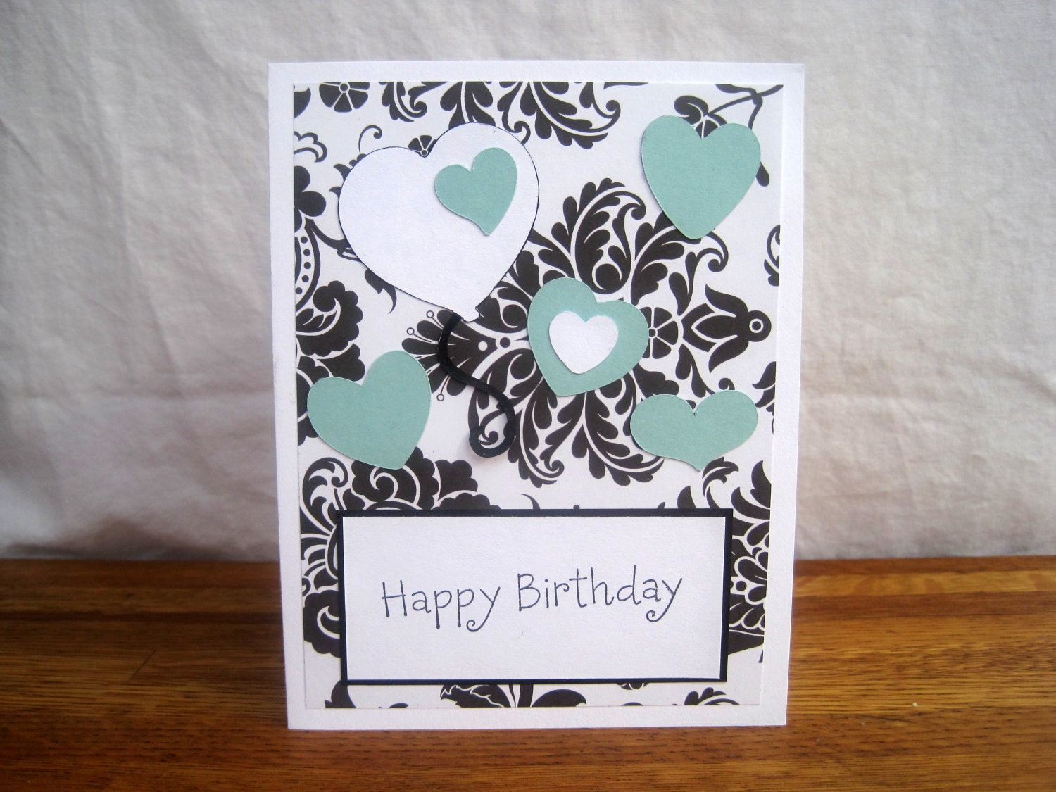 Happy birthday card, 5.5 by 4.25, with black and white floral paper, teal and white hearts, and a stamped sentiment
