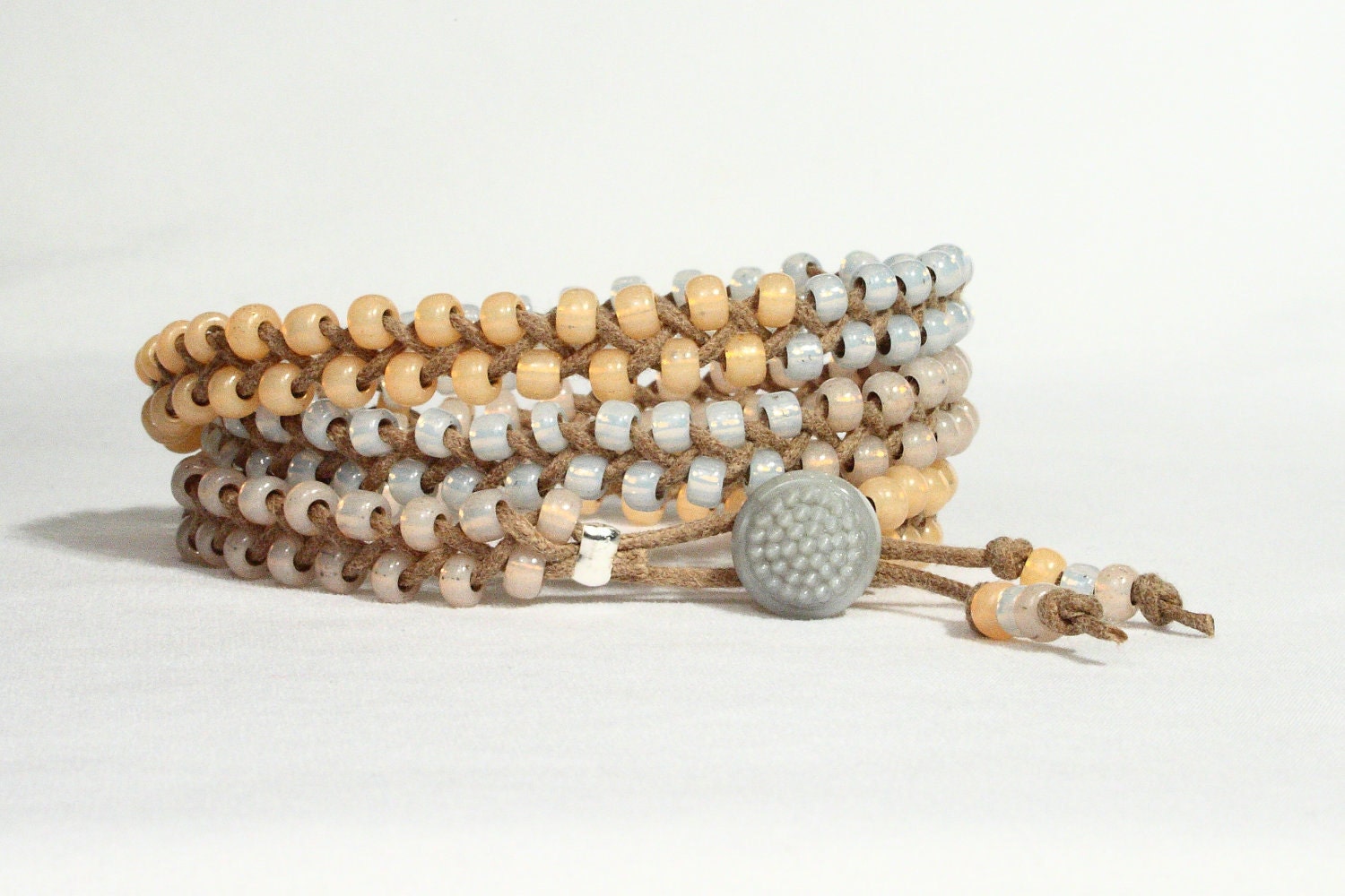 Wrap bracelet braided. Opalescent apricot, pink lavender, gray blue seed beads. Gray button.