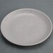 Swirly small porcelain plate glazed in pale blue celadon.