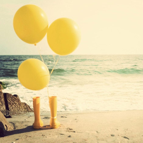 Yellow balloons and rain boots on the beach