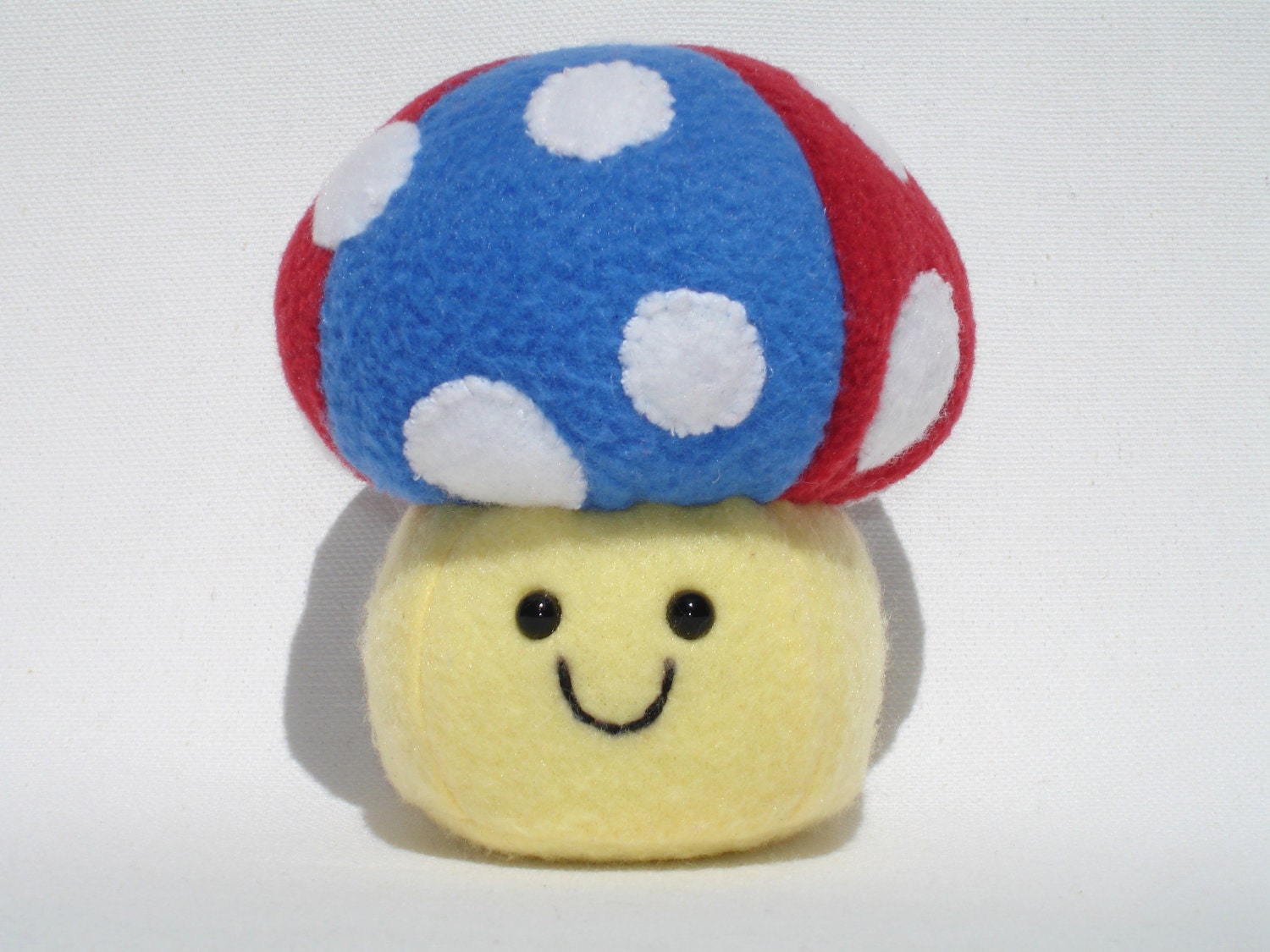Stuffed mushroom toy with red, yellow, and blue fleece and white polka dots