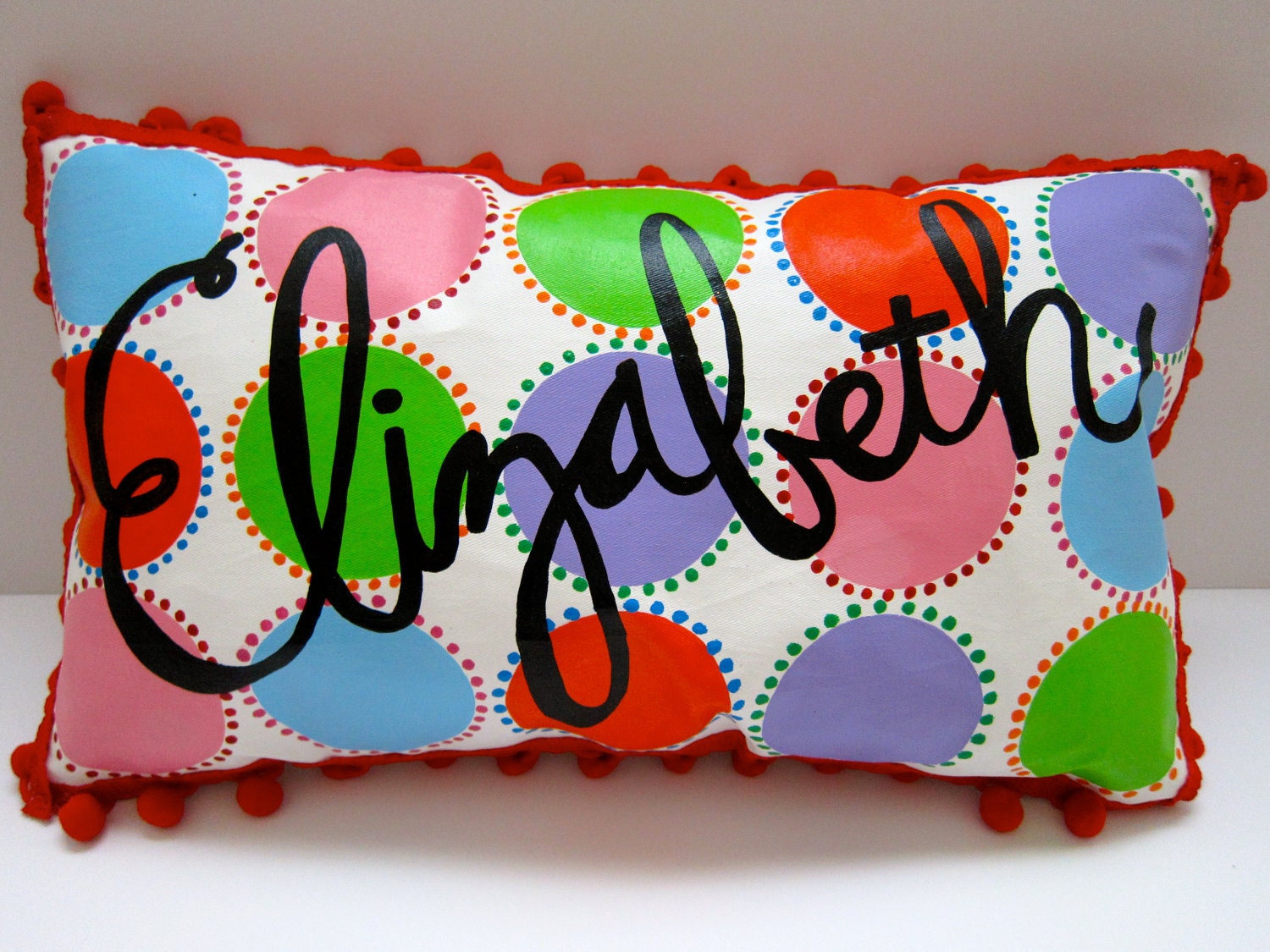Baby pillow in pops of bright and colorful circles. Personalized with name.