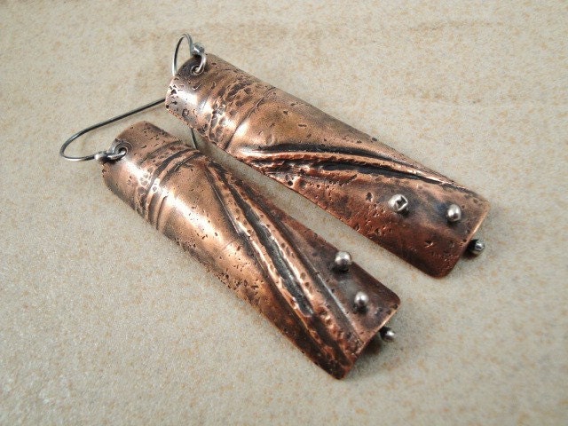 Long copper earrings. Curved. Fold forming. Sterling silver accents. Rich. warm. texture.