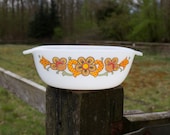 White glass bowl with orange flowers and checkered leaves.