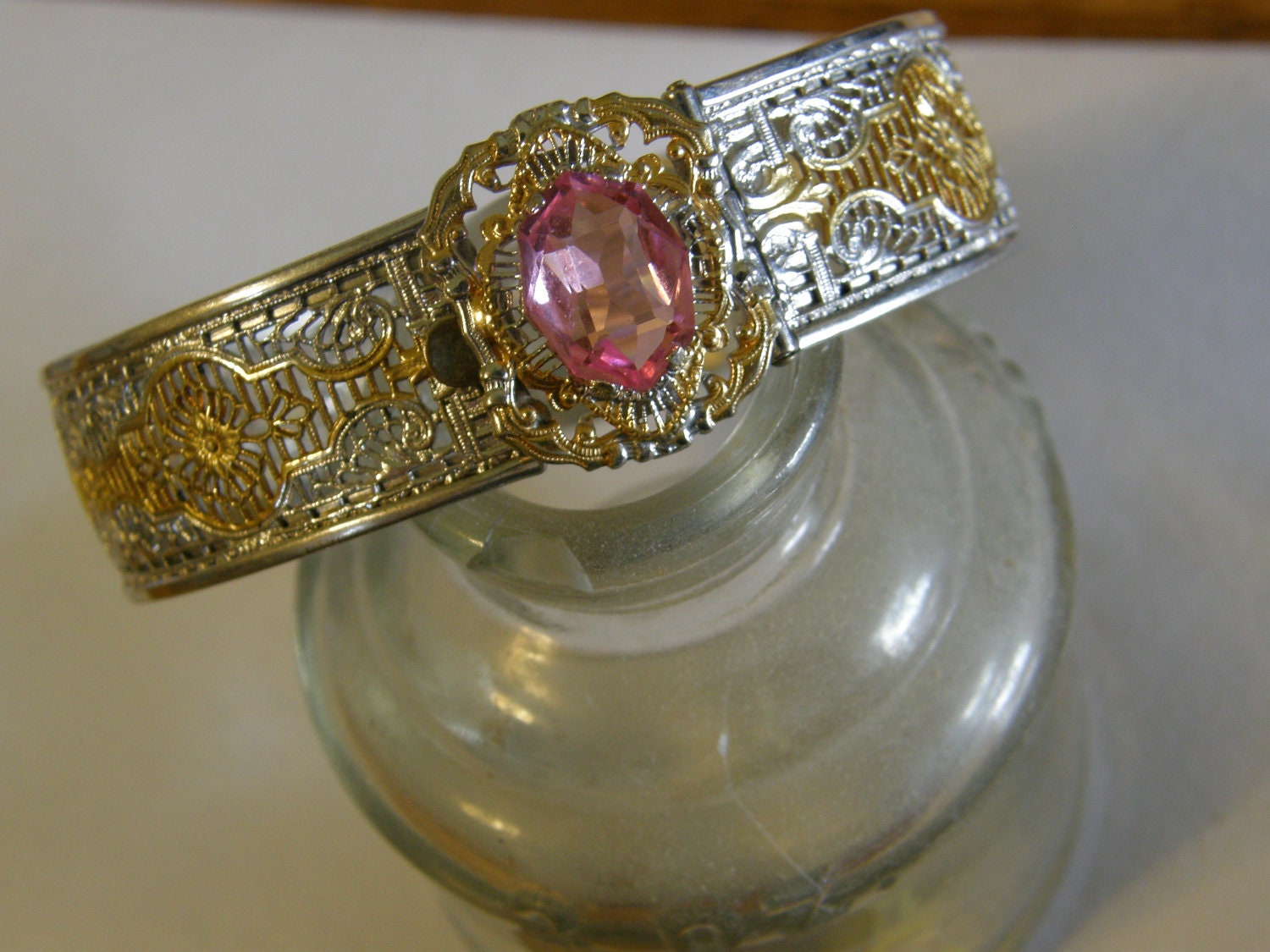 Vintage Art Deco 1930's white and yellow gold tone filigree bangle with pink unfoiled rhinestone and front clasp