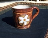 Stoneware coffee mug in 12 oz size with a white daisy medallion