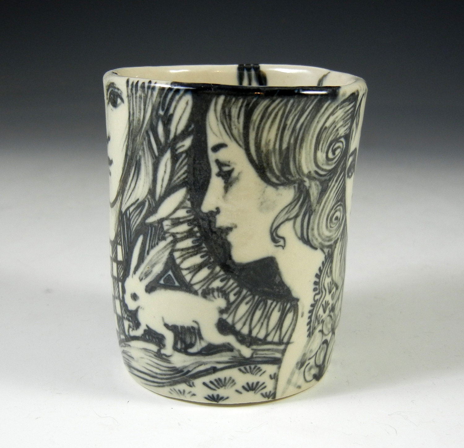 Hand painted black and white porcelain story cup with faces and rabbit