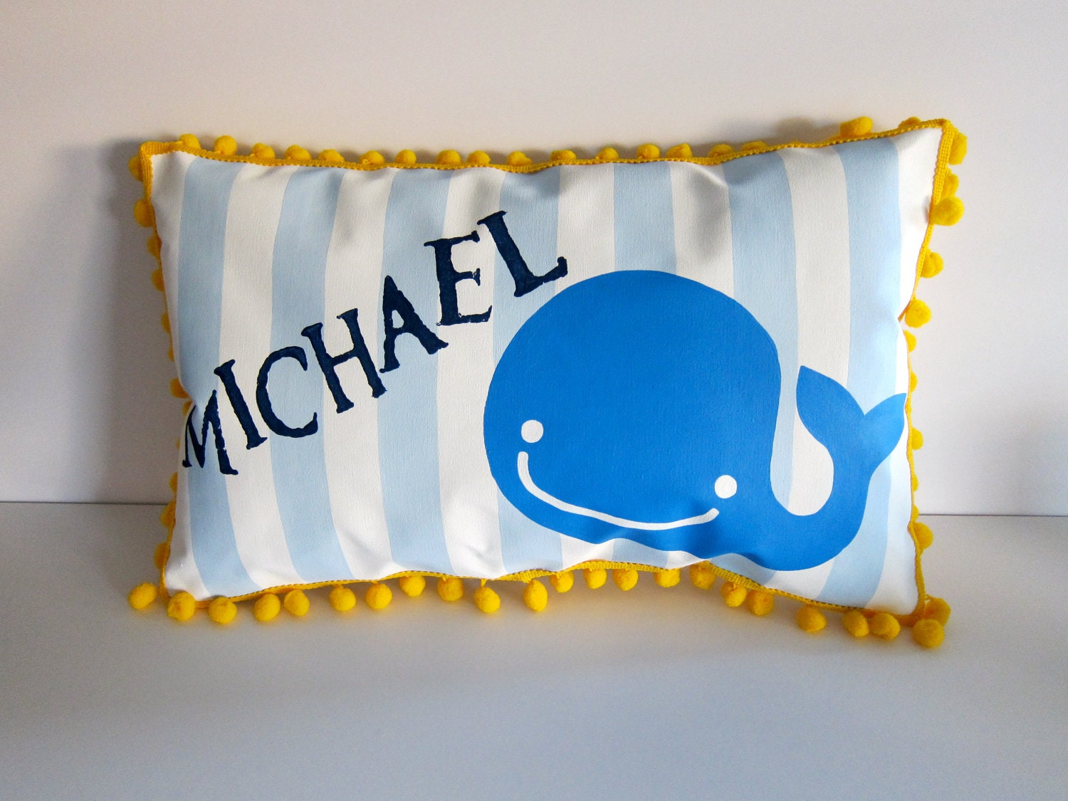 Baby pillow in baby blue stripes and bright blue whale accent.  Personalized with name.