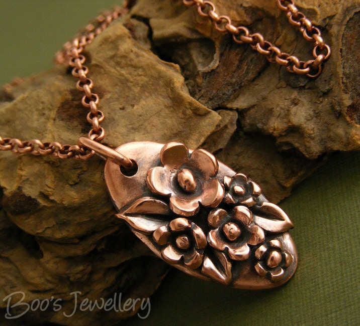 Antiqued copper necklace featuring a hand sculpted oval pendant with flowers and leaves
