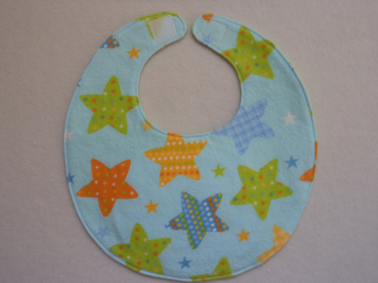 Baby bib, four soft layers, reversible, blue with big orange and green stars