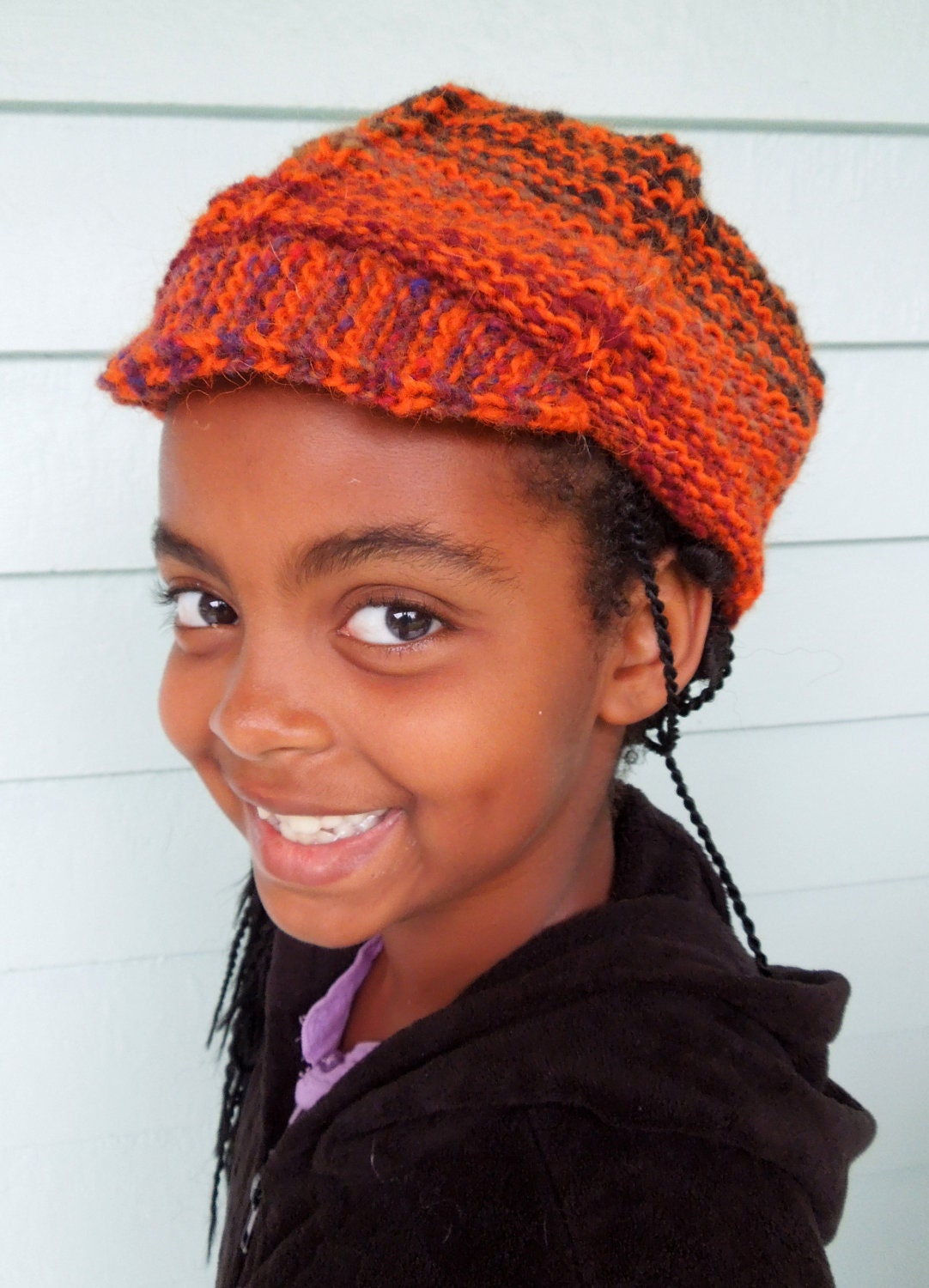 Hat is handknit and all wool.  Solid orange yarn is striped with an earthy Noro yarn making it a great accessory for fall and Halloween too.